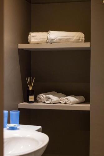 a bathroom with shelves with towels and a sink at Residence Oliveto in Ceriale