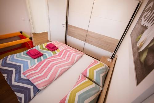 a small bedroom with a bed with colorful sheets at Apartma Sofija, Moravski Dvori in Moravske Toplice
