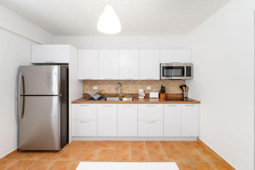 a kitchen with white cabinets and a stainless steel refrigerator at Casa al Mare #3- 1 bdr - 4 min walk to Sandy Beach in Rincon