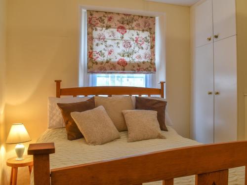 a bedroom with a bed and a window with a curtain at Waterside Cottage in Saltash