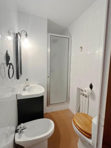 a white bathroom with a toilet and a sink at La Casería in Navaconcejo