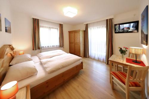 a bedroom with a large bed and a desk with a television at Appartements Wirnsperger in Grossarl