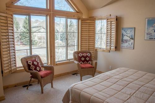 um quarto com uma cama, 2 cadeiras e janelas em Townhomes at River Run - Walk to Ski Lifts and Downtown Ketchum em Ketchum