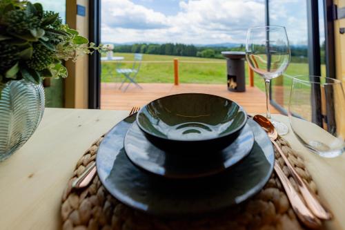 a table with a plate and a glass of wine at Tiny House Rákosníček in Malšín