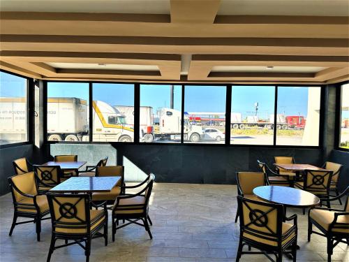 a dining room with tables and chairs and windows at KAVIA MEOQUI HOTEL & SUITES in Meoqui