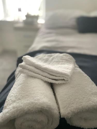 2 handdoeken worden op een bed gestapeld bij Cosy Double Room at The Whitley House in Shinfield