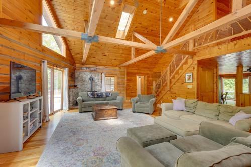 a living room with couches and a tv in a cabin at A-Frame Log Home with Game Room Near Lake George! in Bolton