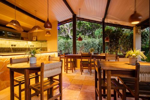 um restaurante com mesas e cadeiras de madeira e janelas grandes em Pousada Carioca - Pousada de Charme em Jericoacoara