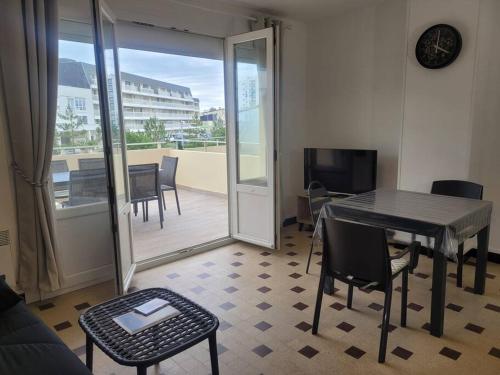 salon ze stołem i krzesłami oraz balkonem w obiekcie Appartement familial terrasse vue mer avec parking w mieście Berck-sur-Mer