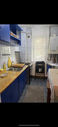 een keuken met blauwe kasten, een wastafel en een tafel bij Apartament in Craiova
