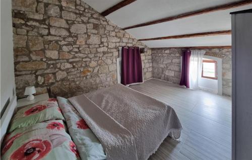 een slaapkamer met een bed en een stenen muur bij Nice Apartment In Funtana With Kitchen in Funtana