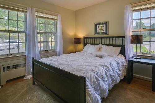 a bedroom with a large bed and two windows at Cumberland Cottage with Screened Porch and Fire Pit! in Cumberland