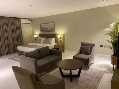 アブジャにあるKnightsbridge Hotel & Suitesのベッド、ソファ、椅子が備わるホテルルームです。