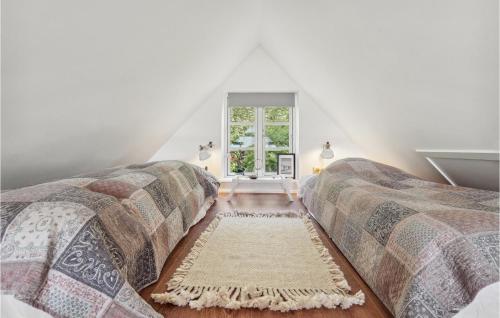 a attic bedroom with two beds and a window at 2 Bedroom Awesome Home In Haarby in Hårby