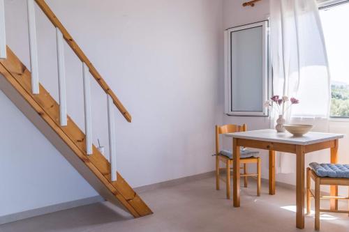 a dining room with a table and a staircase at Marianthi Apts Anissaras in Hersonissos