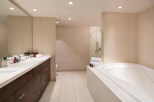 uma casa de banho com uma banheira, 2 lavatórios e um chuveiro em Chicago Marriott Naperville em Naperville