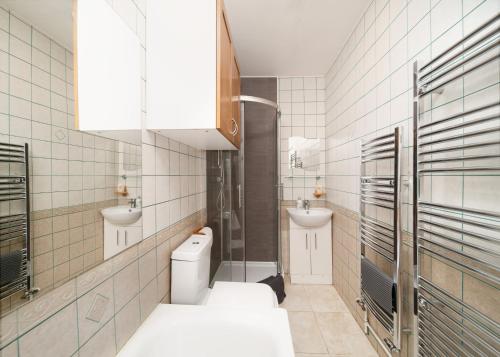 a white bathroom with two sinks and a toilet at Excel 5min CUSTOM HOUSE STATION parking WIFI sleeps 6 in London