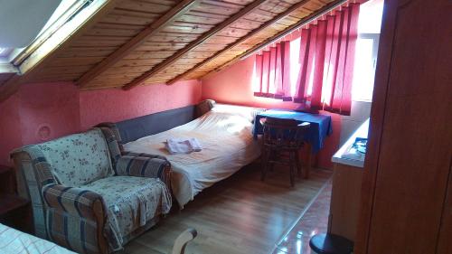 um pequeno quarto com uma cama, uma cadeira e uma mesa em Lovac em Štrpce