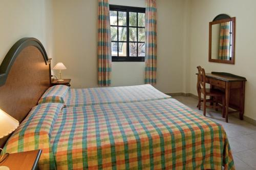 1 dormitorio con cama, escritorio y ventana en Apartamentos Las Mozas, en Valle Gran Rey