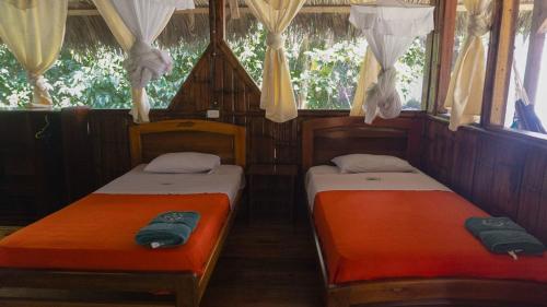2 Betten in einem Zimmer mit Fenstern in der Unterkunft Caiman Lodge in Cuyabeno