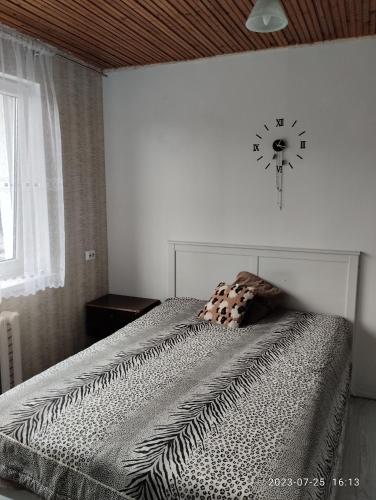 1 dormitorio con 1 cama con reloj en la pared en Kambariu nuoma Tytuvenuose en Tytuvėnai