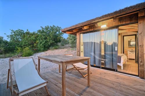 a wooden deck with a table and a chair at Golden Haven Luxe Bungalow Resort in Murter