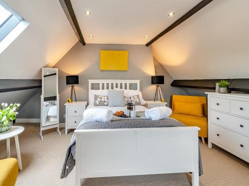 1 dormitorio con cama blanca y sofá amarillo en Bo Peep Cottage, en Thornton Dale