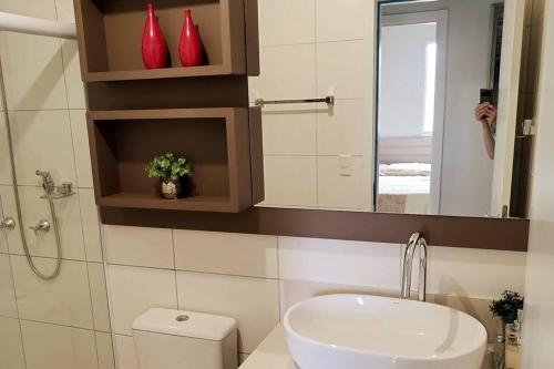 a bathroom with a toilet and a sink and a mirror at Apto Centro de Criciúma in Criciúma
