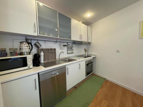 une cuisine avec des placards blancs et un tapis vert dans l'établissement Burgães II Apartment, à Porto