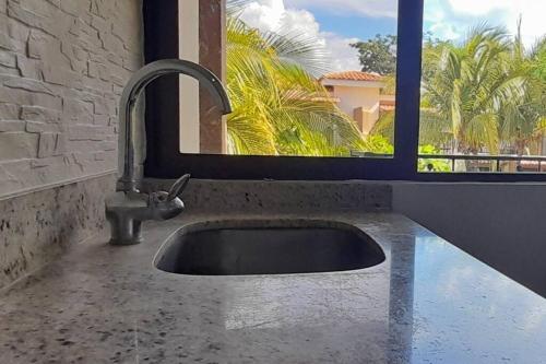 a sink in a bathroom with a window and palm trees at Jade Beach B apartamento 20 in Coco