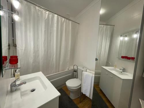 a white bathroom with a toilet and a sink at Burgães II Apartment in Porto