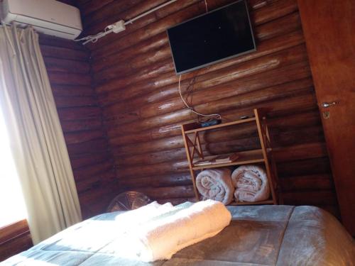 a bedroom with a wooden wall with a television above a bed at Monte Sion cabañas & relax in San Javier