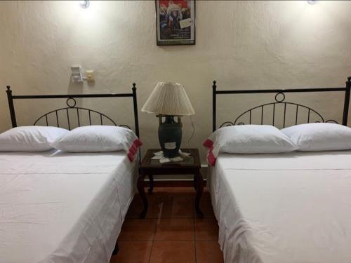 2 Betten in einem Zimmer mit einem Tisch und einer Lampe in der Unterkunft Hotel Jacaranda in Tuxtla Gutiérrez