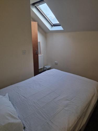 1 dormitorio con 1 cama blanca grande y tragaluz en Cozzy 2 roooms with 2 beds, en Bradford