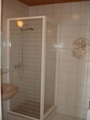 um chuveiro com uma porta de vidro ao lado de um lavatório em Kings Pension em Gyenesdiás