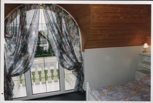 um quarto com uma janela com cortinas e uma varanda em Kings Pension em Gyenesdiás
