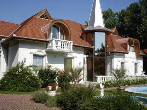 uma igreja com um campanário branco e uma casa em Kings Pension em Gyenesdiás