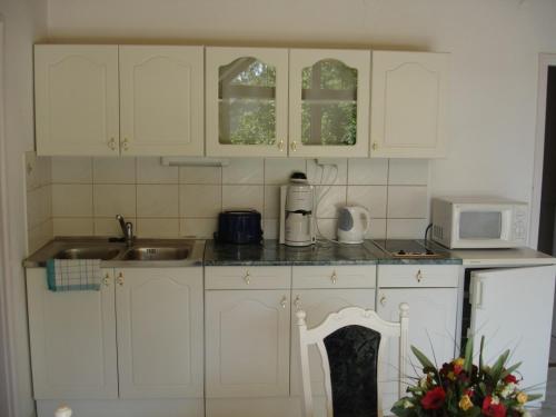 uma cozinha com armários brancos, um lavatório e um micro-ondas em Kings Pension em Gyenesdiás