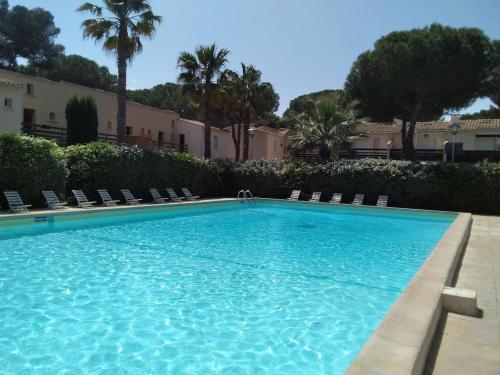une grande piscine bleue avec des chaises et des palmiers dans l'établissement Studio avec jardin, piscine, sauna, proche de la mer et du village naturiste, au Cap d'Agde