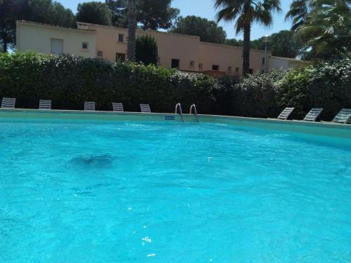 une grande piscine bleue avec des chaises et un bâtiment dans l'établissement Studio avec jardin, piscine, sauna, proche de la mer et du village naturiste, au Cap d'Agde