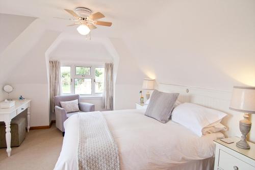 a white bedroom with a bed and a chair at Twiga House Bed and Breakfast in Wareham