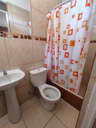 a bathroom with a toilet and a sink and a shower curtain at 1 habitación - 4 huéspedes in Oxapampa