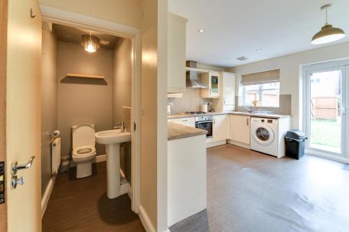 a kitchen with a toilet and a sink and a washing machine at Simitach Serviced Apartments in Middleton