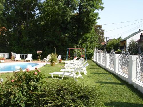 une rangée de chaises blanches dans l'herbe près d'une piscine dans l'établissement Kings Pension, à Gyenesdiás
