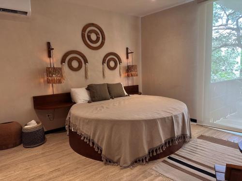 um quarto com uma cama e uma grande janela em Ophelia Tulum Condo Hotel in Aldea Zama em Tulum