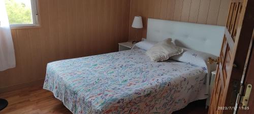 1 dormitorio con cama con edredón y almohada en Planta superior independiente con piscina - barbacoa, 
