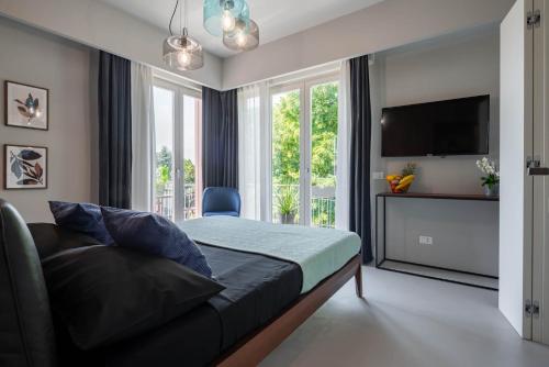 1 dormitorio con 1 cama, TV y ventanas en Officine Cavour - Appartamenti la Quercia en Padova