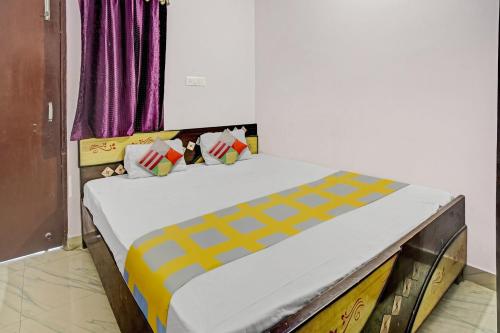 Super OYO Hotel Happy Inn في باتنا: غرفة نوم بسرير كبير بخطوط صفراء وصفراء