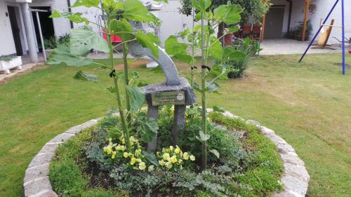 a garden with a bird statue in the grass at Gästehaus und Weinbau Zur Wiederkehr Strudler in Podersdorf am See