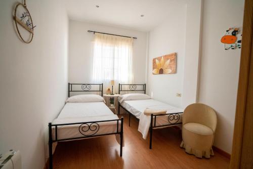 Zimmer mit 2 Betten, einem Tisch und einem Stuhl in der Unterkunft Villa Entre dos Tierras in Otura